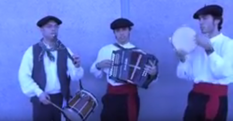 Three Basque musicians in traditional costumes play typical Basque instruments