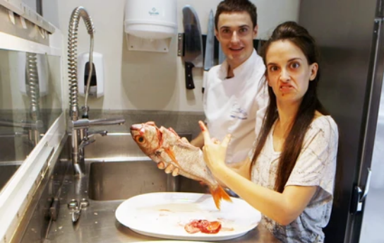 chef and woman holding fish in restaurant