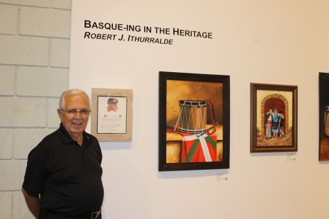Basque artist Bob Ithurralde stands in front of some of his paintings at an exhibit of his work