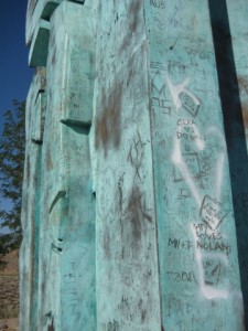 Graffiti is scratched in and spraypainted on the statue.